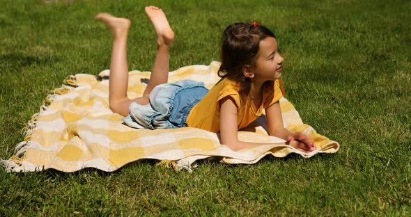 Child lying on the blanket, on the grass in the sun day, take sunbathes on backyard