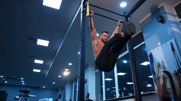 Muscular man doing exercises on horizontal bar in gym