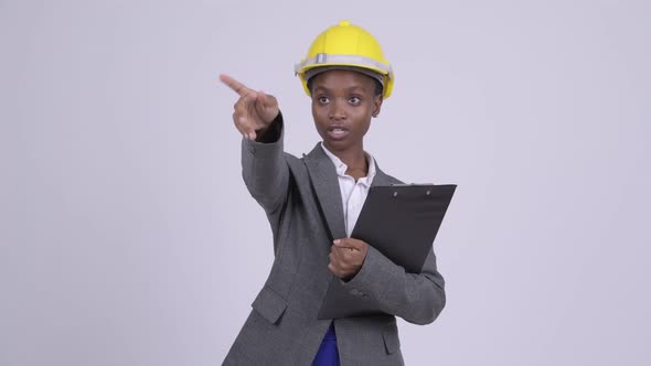 Young African Businesswoman Wearing Hardhat Directing with Clipboard