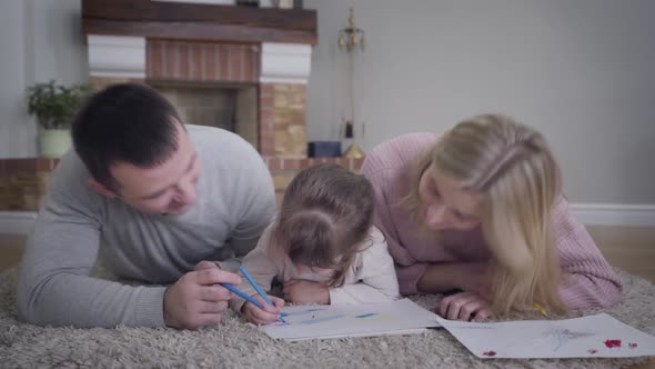 Close-up of Smiling Caucasian Man and Woman Kissing Little Girl on Cheeks Simultaneously. Cute