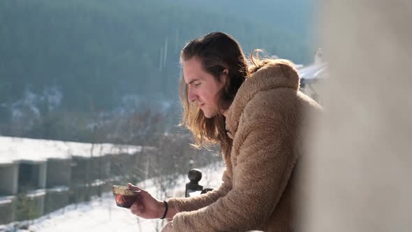 Man drinking tea on balcony.