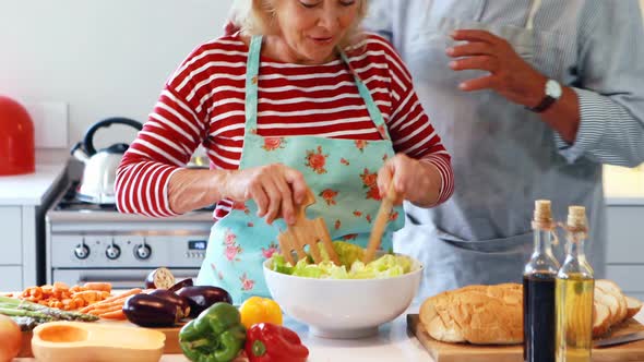 Couple preparing salad in kitchen