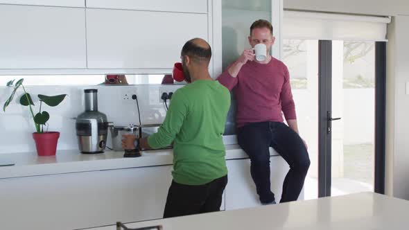 Multi ethnic gay male couple drinking coffee in kitchen