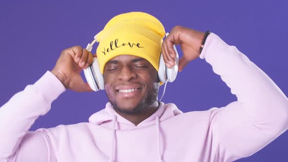 Cute African-American Man in Headphones Dressed in Street Style Wear, Listening To Music