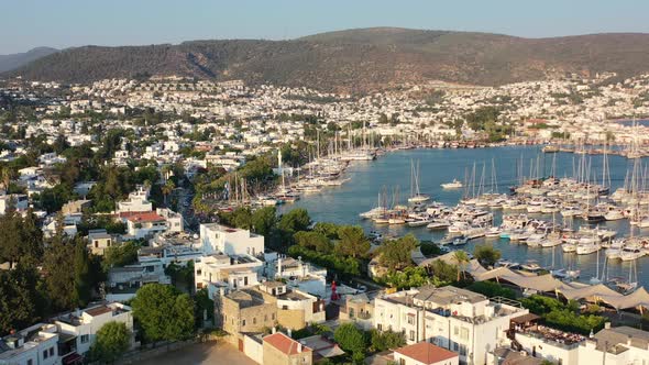 aerial drone flying over Bodrum marina full of sailboats on a summer afternoon with the sun setting