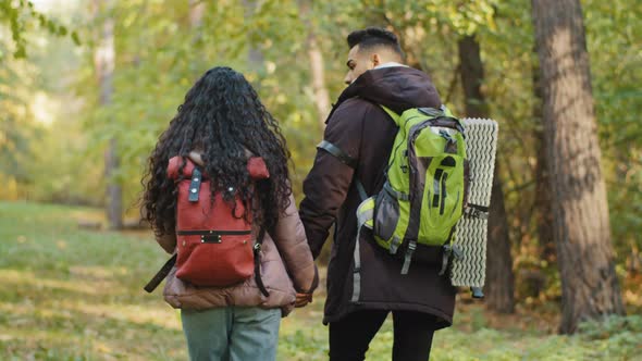 Back View Young Active Healthy Couple in Love Tourists Travelers Travel with Backpack in Forest Walk