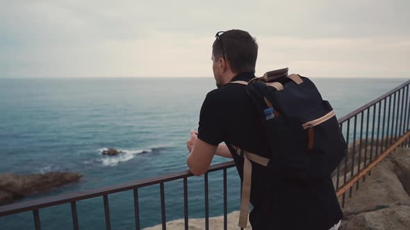 Sorrowful Adult Man Is Watching Alone on Ocean View in Evening Time From Rock