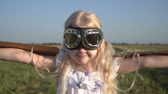 Portrait of a Child Girl in the Image of an Airplane Pilot with Cardboard Wings