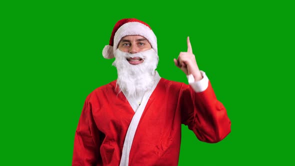 Santa Claus in Red Suit Pointing Up on Green Chroma Key Background