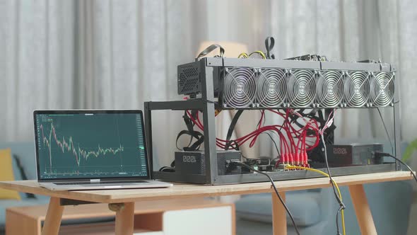 A Laptop Showing Crypto Chart Is On The Table With Mining Rig For Mining Cryptocurrency