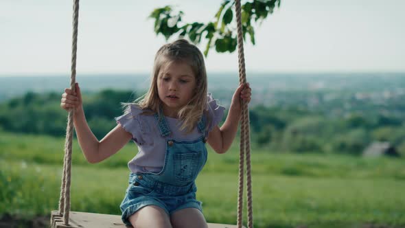 Blonde girl swinging high in summer day