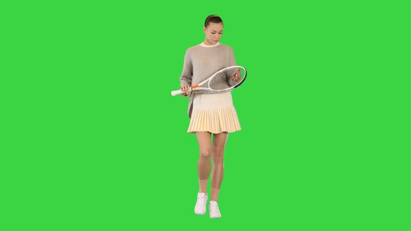 Beautiful Girl Athlete Walking and Looking at Tennis Racket on a Green Screen Chroma Key