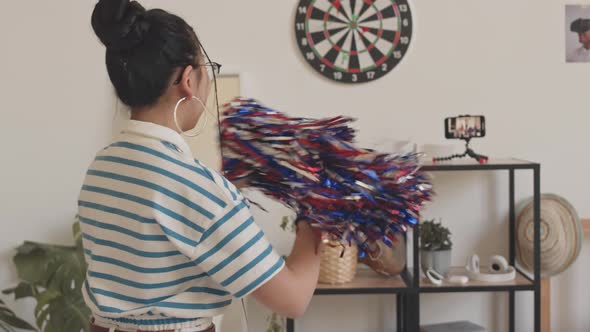 Teenage Cheerleader Girl Dancing with Pom Poms at Home