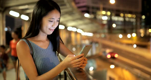 Woman looking at mobile phone in the city at night 