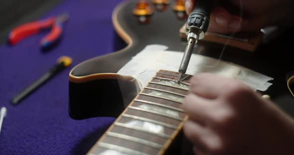 Luthier Heats Frets on Guitar By Soldering Iron Before Refretting Preparations for Frets Replacement