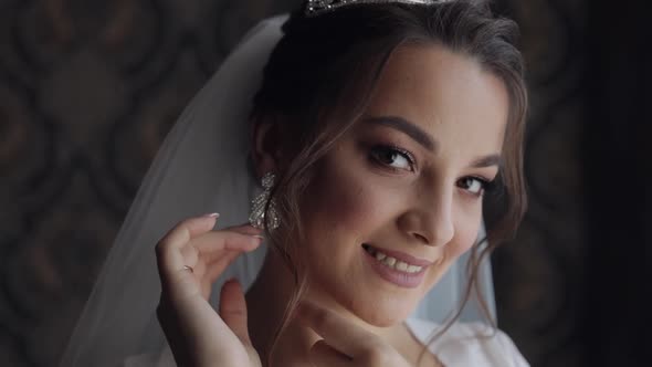 Bride in Boudoir Dress Wears Earrings. Wedding Morning Preparations. Woman in Night Gown and Veil