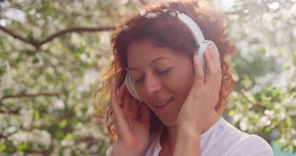 Woman with Headphones in a Blooming Orchard