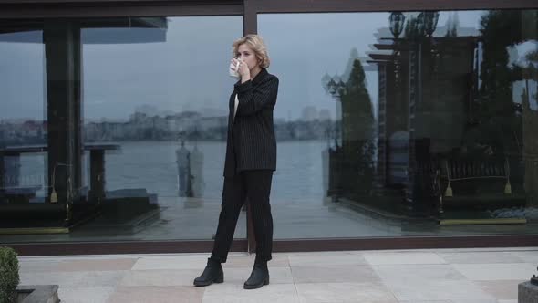 Pretty Girl Drinks a Cup of Tea and Looks Around at Home in Windy Day