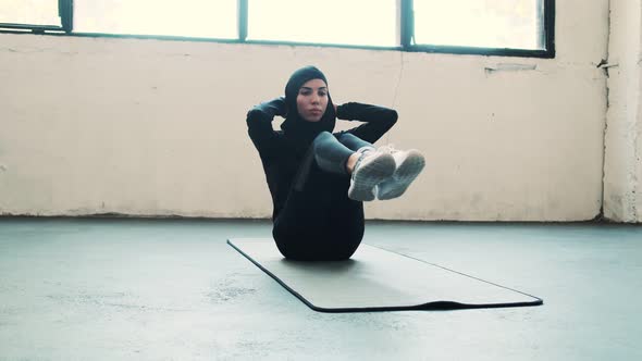 A focused arabian sports woman wearing a national hijab is pumping press