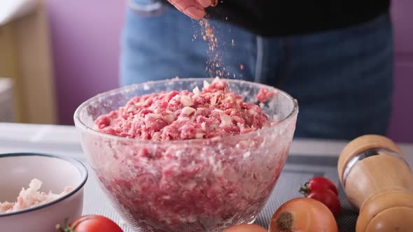 Adding Salt and Spices to Minced Meat with Onion and Spices in a Glass Bowl Making Cutlets