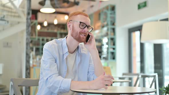 Redhead Man Talking on Smartphone in Cafe