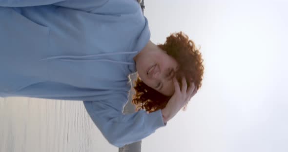 charismatic plump girl with freckles waves her curly hair straightens her hand smiling