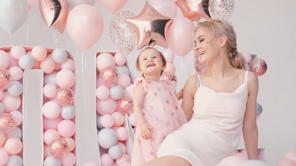 Little Cute Girl and Her Mom Smile with Colorful Balloons White and Pink in Birthday Decoration