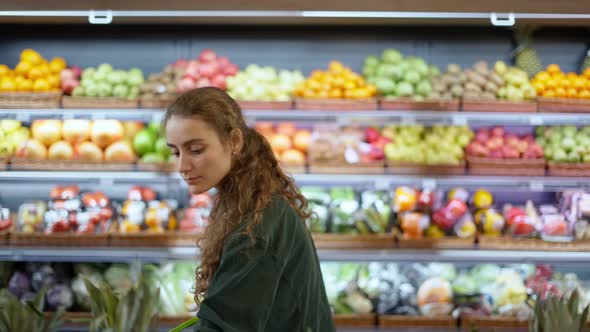 Female Customer Comparing Different Fruits at the Food Counter