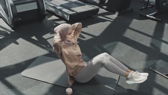 Woman in Hijab Doing Abs Exercise in Gym