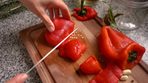 Hands Chopping Roasted Red Bell Pepper On Wooden Board. Preparing Bell Peppers In Oil In The Kitchen