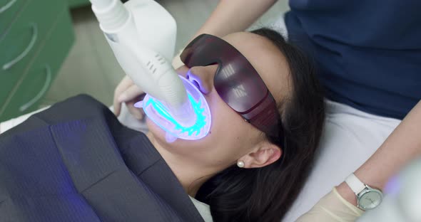 Dentist Whitening Teeth for Patient in Medicine Dental Clinic with Lamp