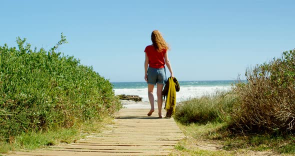 Woman walking towards sea on boardwalk 4k