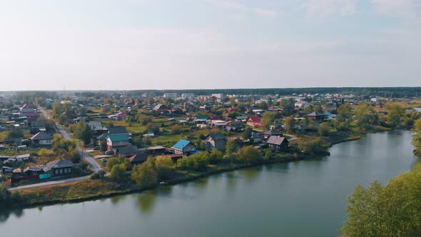 The Drone Flies Over a Small Town on the River Bank the Outskirts of a City with Small Private