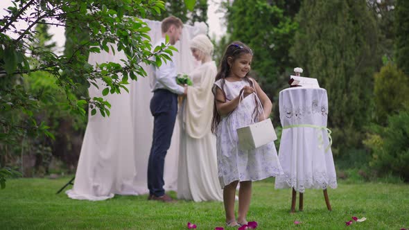 Cute Excited Middle Eastern Flower Girl Throwing Roses Petals Smiling with Blurred Happy Loving