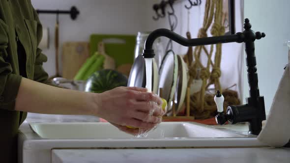 Woman washing lemon under water at kitchen