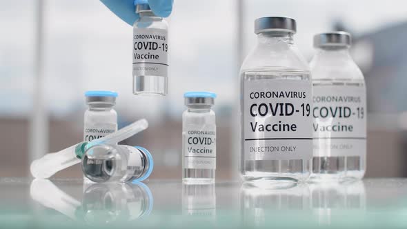 Nurse Wearing Gloves Puts a Test Tube with a Coronavirus Treatment Vaccine