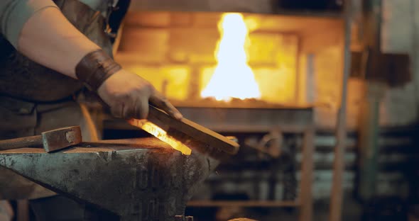 Blacksmith Brushes the Metal with a Brush on the Anvil