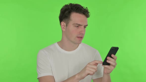 Young Man Loss on Smartphone on Green Background