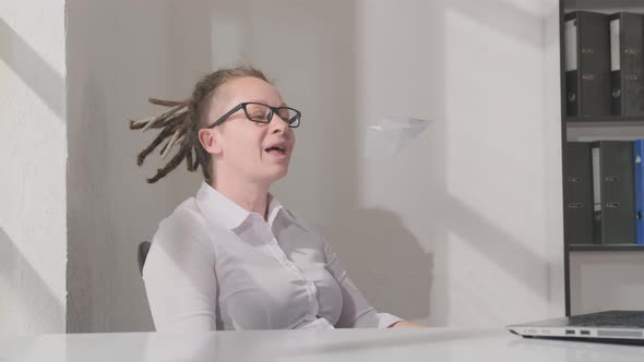 Dreaming woman about long-awaited vacation in office is played with paper airplane