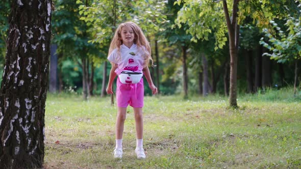 Child actively playing and moving fun. Little schoolgirl dances outdoors and rejoices