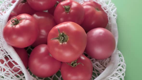 Fresh Ripe Tomatos in a Ecological Zerowaste Net Bag Placed on Green Background