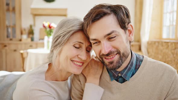 Close Up Portrait of Young Loving Son Cuddling Together with His Beautiful Senior Mother Enjoying