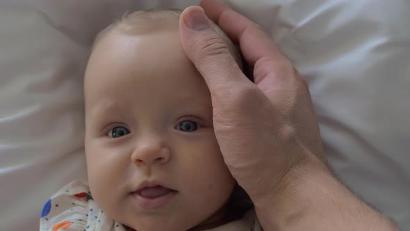 A Closeup of a Baby Girl's Face and a Father's Hand Touching Her