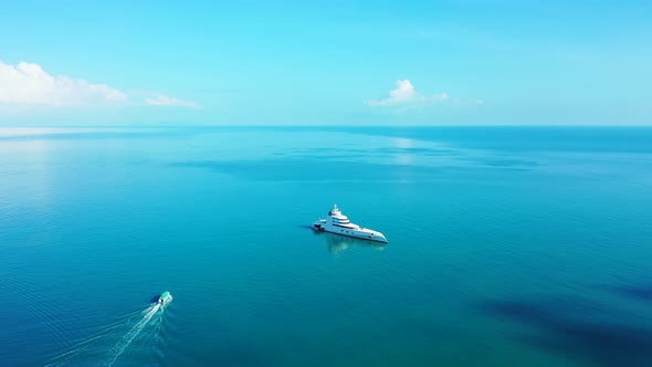 Beautiful big yacht anchoring on calm blue turquoise lagoon and boat sailing near shore of tropical