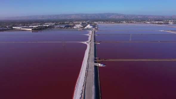 Flying straight over pathway in maroon colored salt ponds in East bay area, Northern California