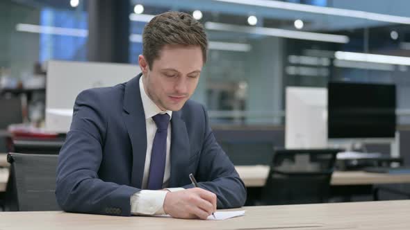 Businessman Writing on Paper in Office