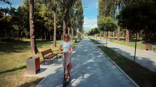 Woman Ride On Electric Scooter Mobility.E-Scooter Rider Rent Personal Eco Transport.