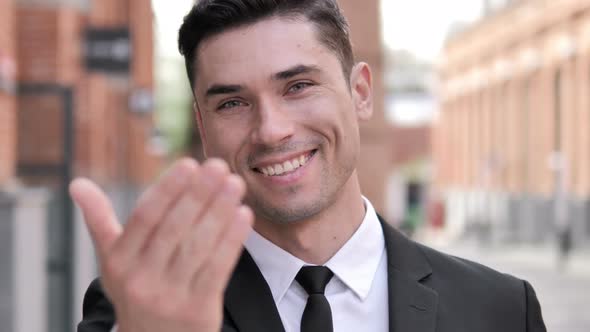 Outdoor Inviting Gesture by Young Businessman