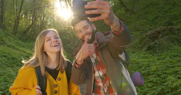 A Guy and a Girl Are Taking Selfies and Walking Through the Forest