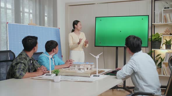 Asian Woman Engineer With Solar Cell Presenting About The Green Screen Tv At The Office